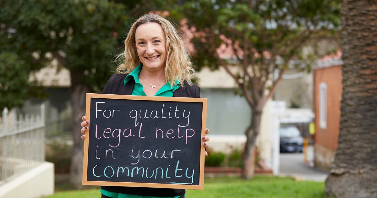Smiling woman holding a chalkboard that reads "For quality legal help in your community"